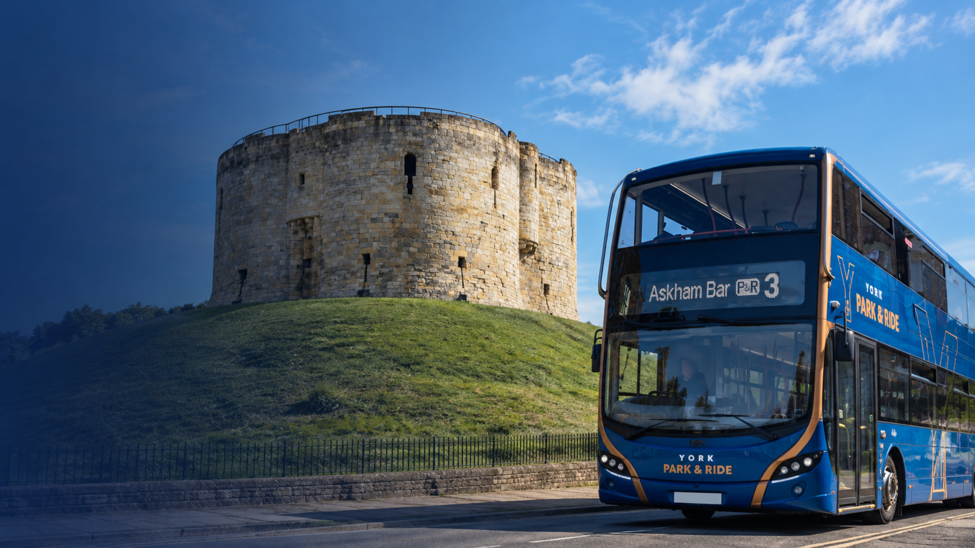 A blue York Park and Ride double-decker showing route 3 to Askham Bar, passing Clifford's Tower on its grassy mound under a blue sky.