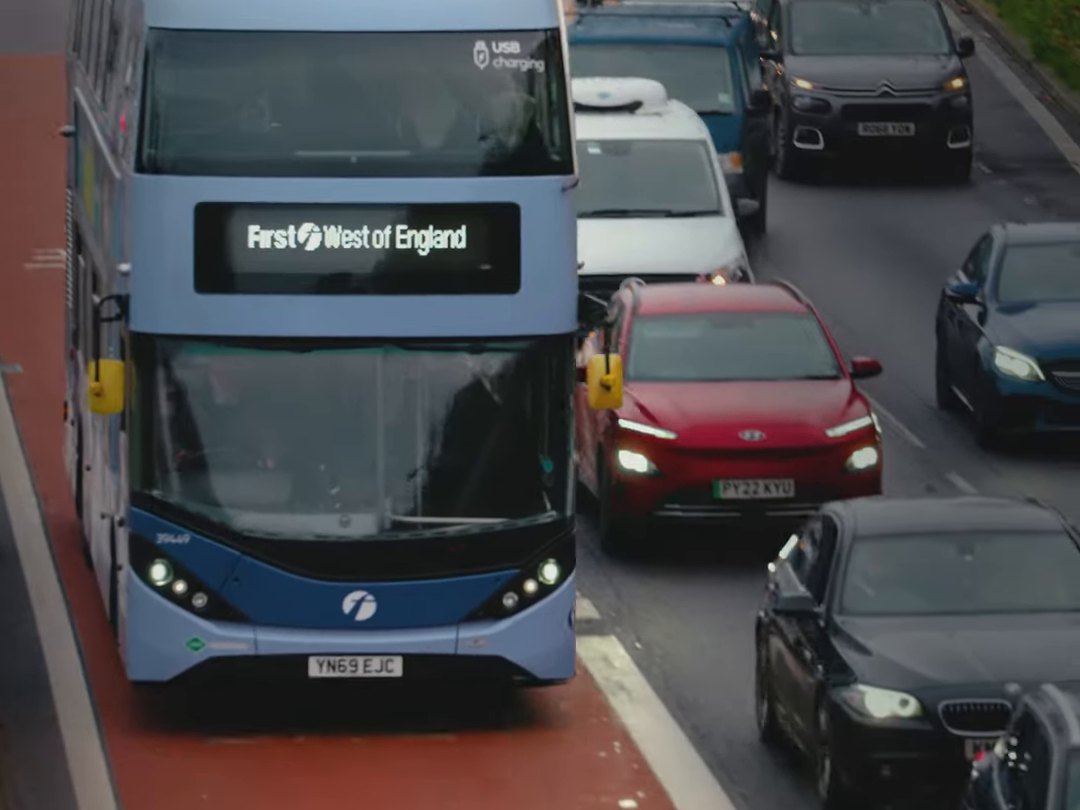 A First West of England double-decker bus in a red bus lane beside queuing traffic, a still from the recruitment film