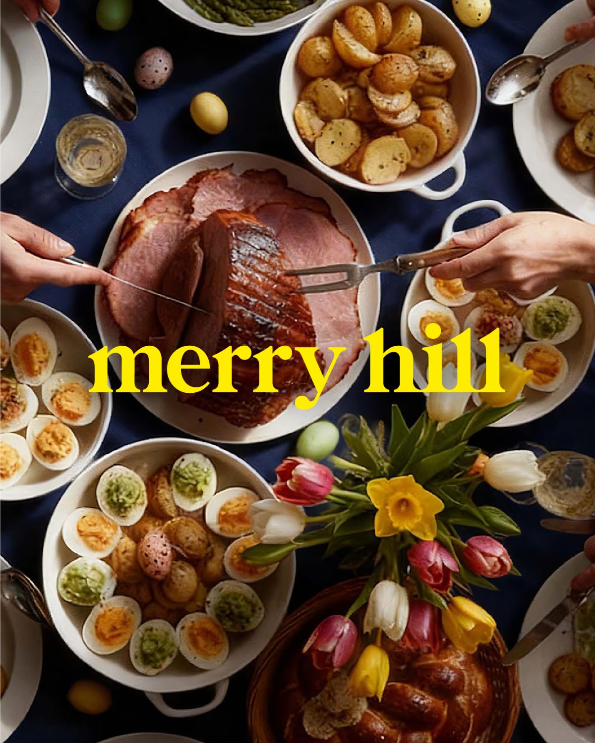 Merry Hill Easter artwork showing an overhead view of an Easter lunch table, a glazed ham being carved among roast potatoes, devilled eggs, tulips and daffodils, under the Merry Hill logo in yellow.