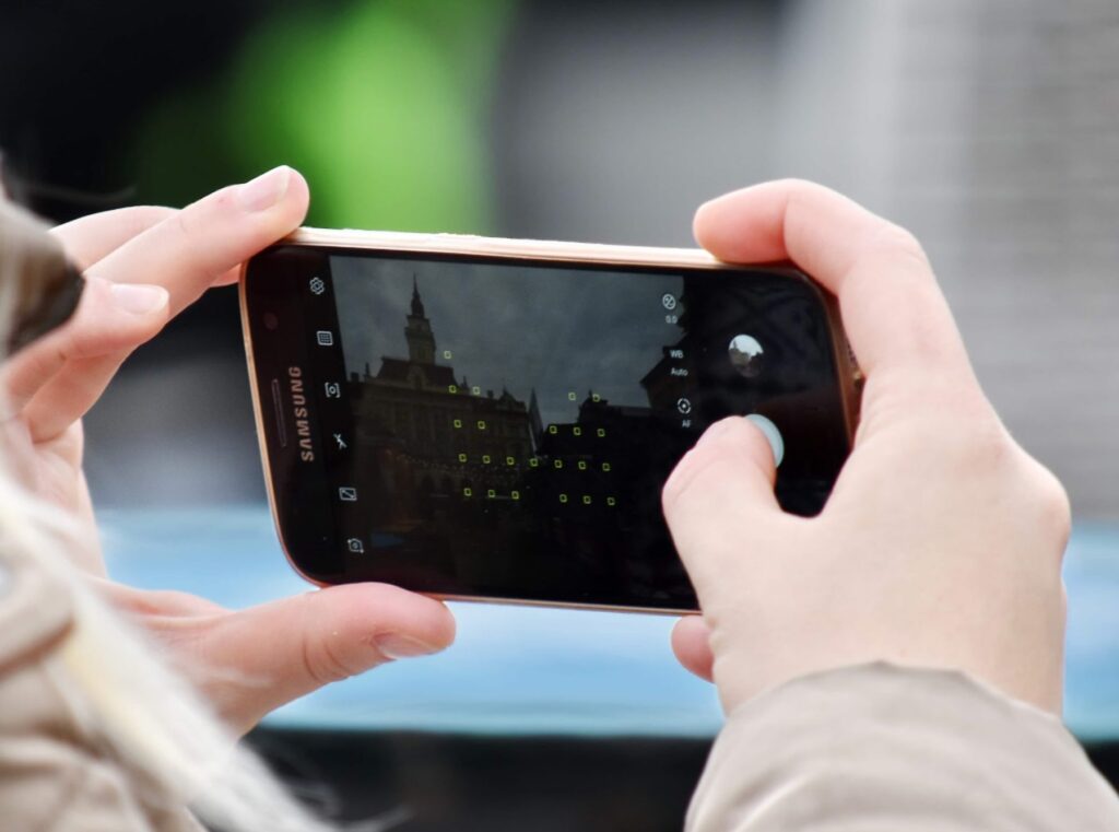 Hands taking a photograph of a city square on a smartphone camera